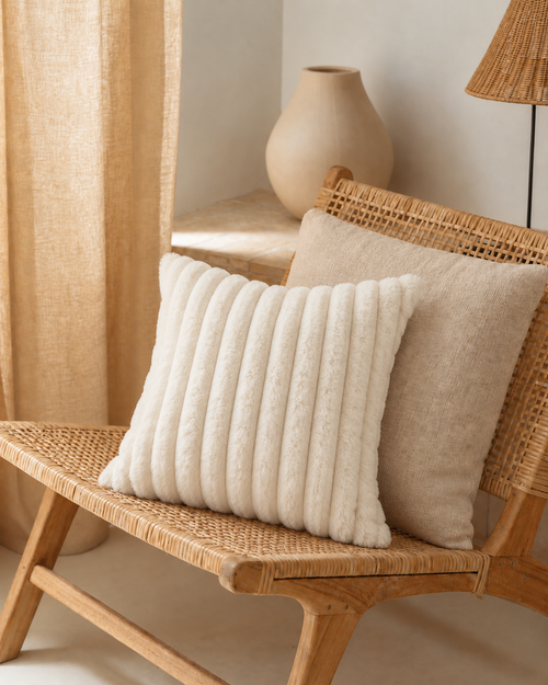 Channel Faux Fur Pillow Cover in Ivory, on a rattan armchair