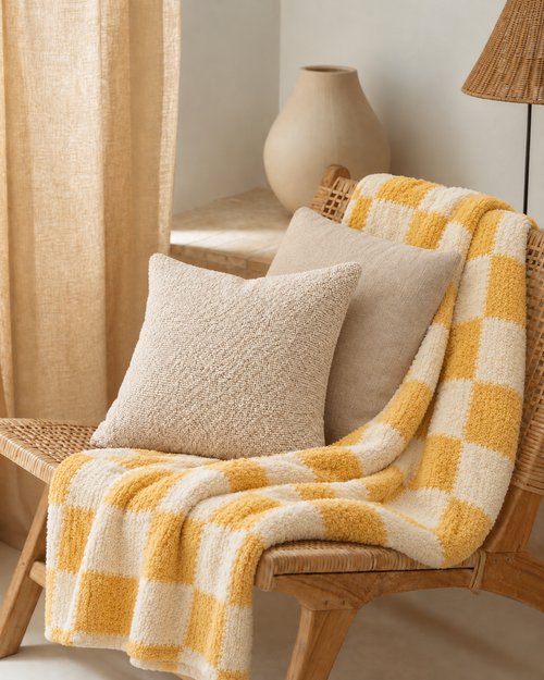 Checkered Cotton Chenille Throw in Yellow, on a rattan armchair