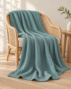 Four-Layer Cotton Gauze Throw, draped over a rattan armchair