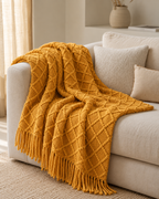 Fringed Diamond Knit Cotton Throw in Mustard, on a linen sofa