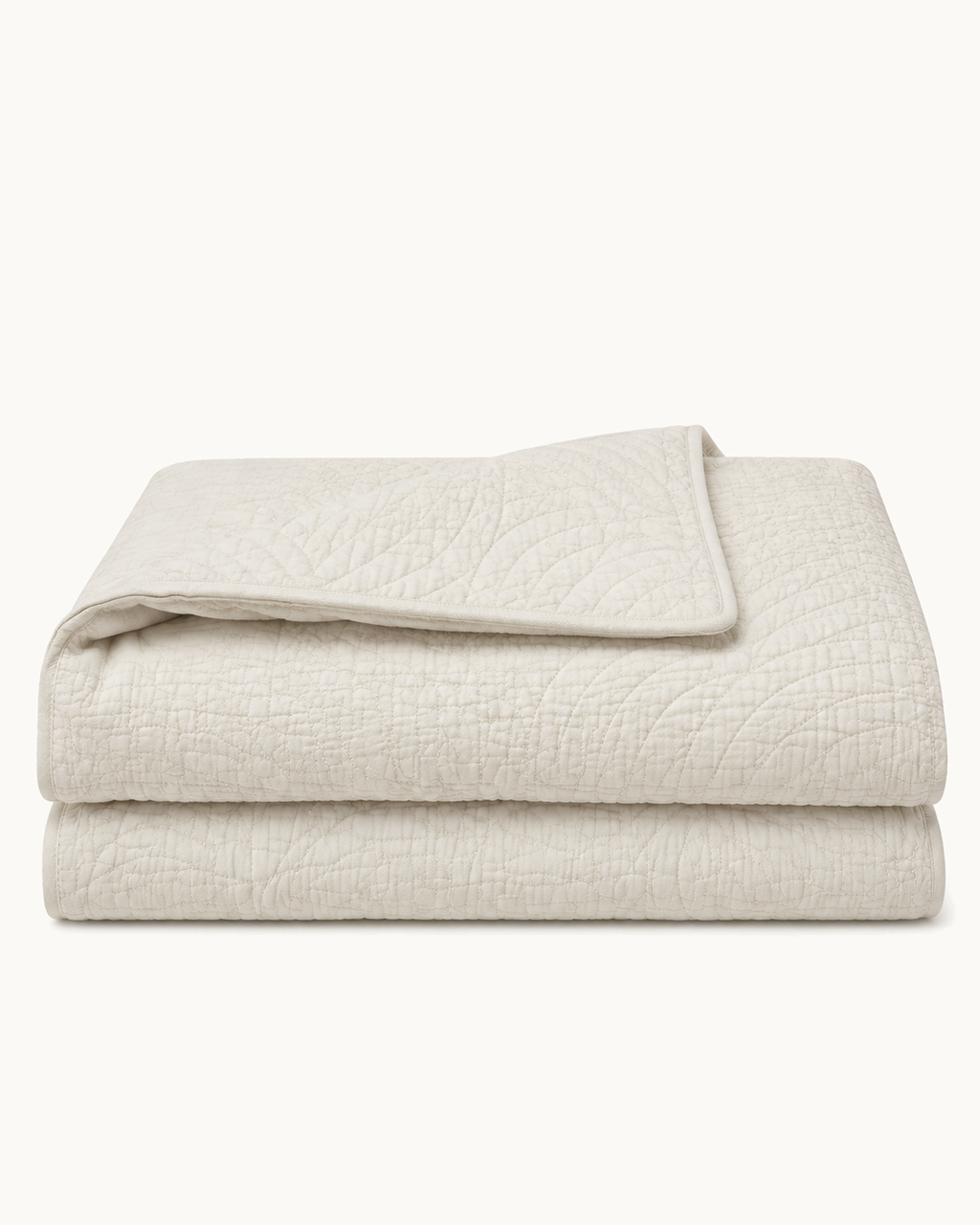 Quilted Cotton Coverlet, folded with one corner turned to show both faces, on a plain background